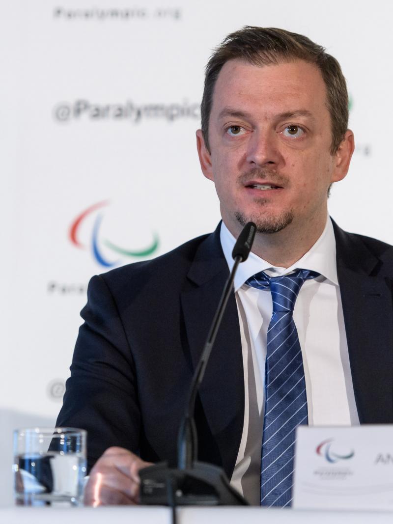 Andrew Parsons speaking into a microphone while sitting on a stage