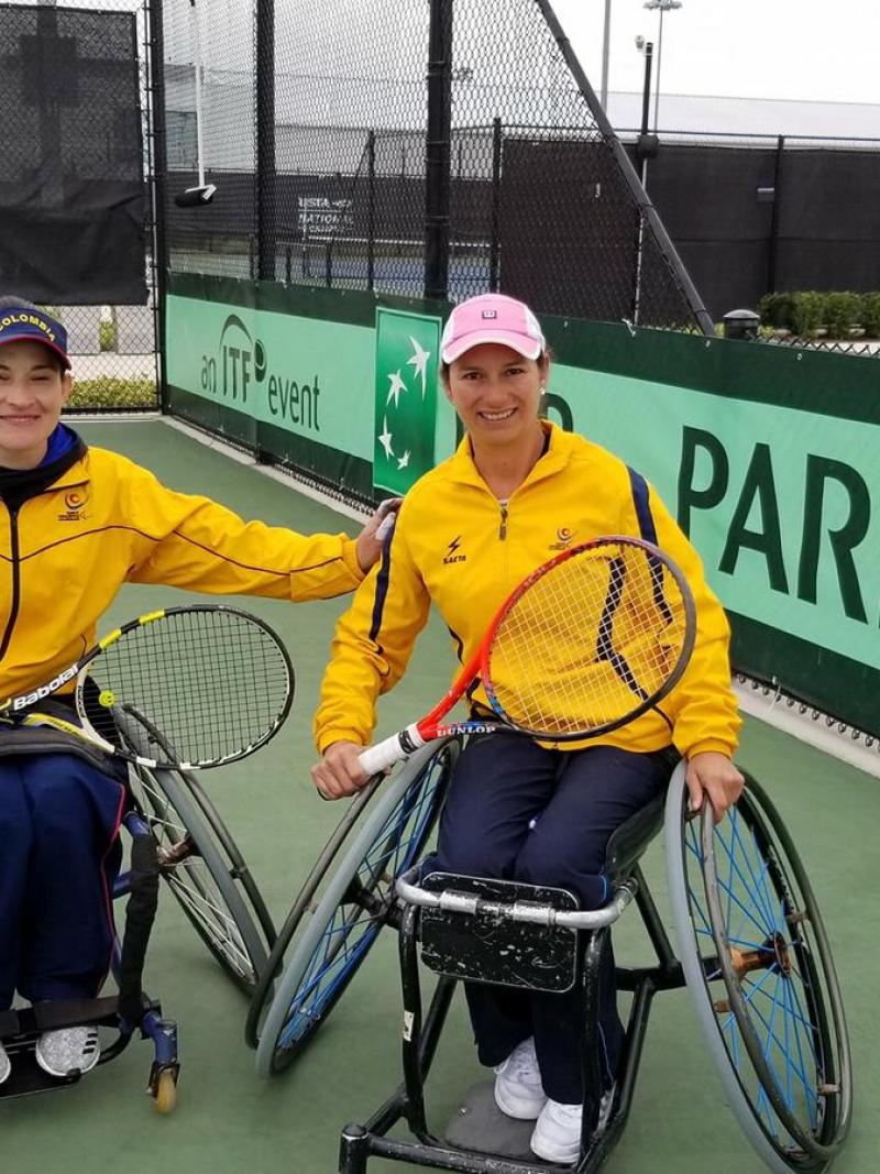 Johanna Sosa and Johana Martinez smiling and holding their rackets while wearing Colombia's official uniforms
