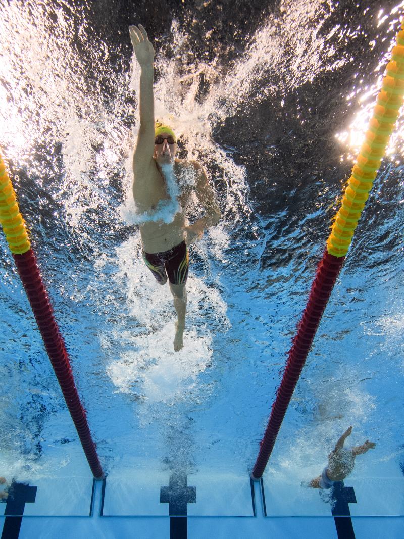 Man swimming in a pool seeing from under the pool