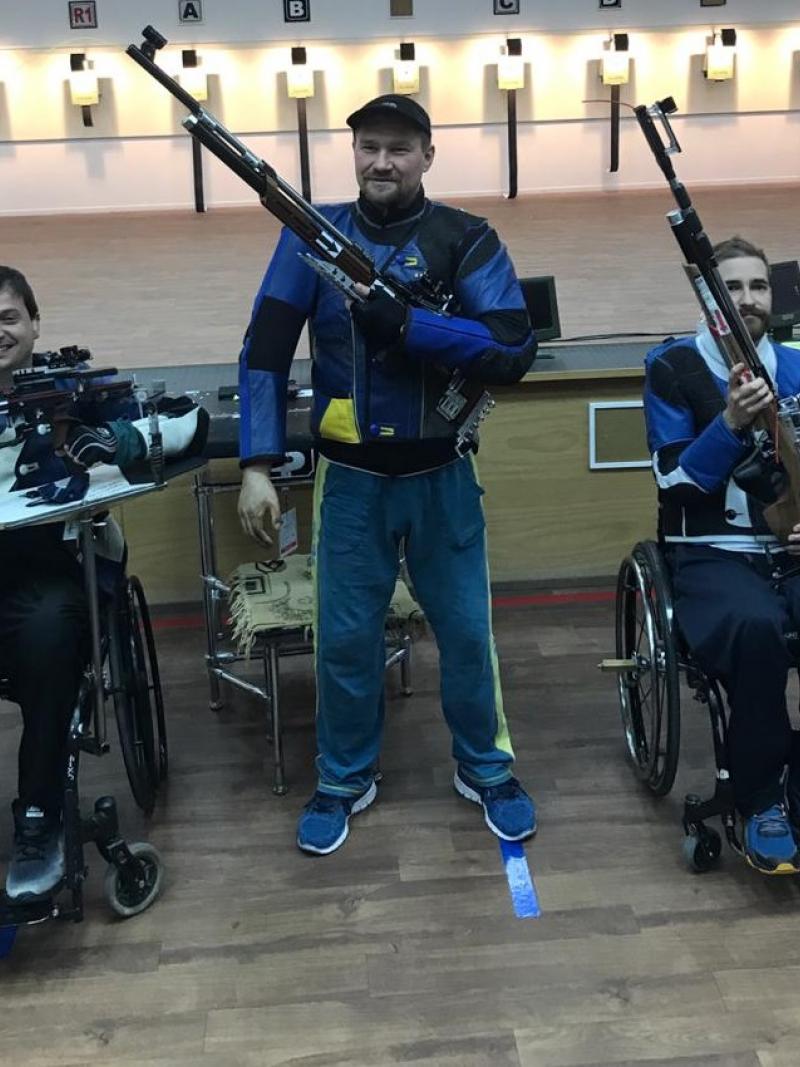 Three male medallists pose with their rifles 