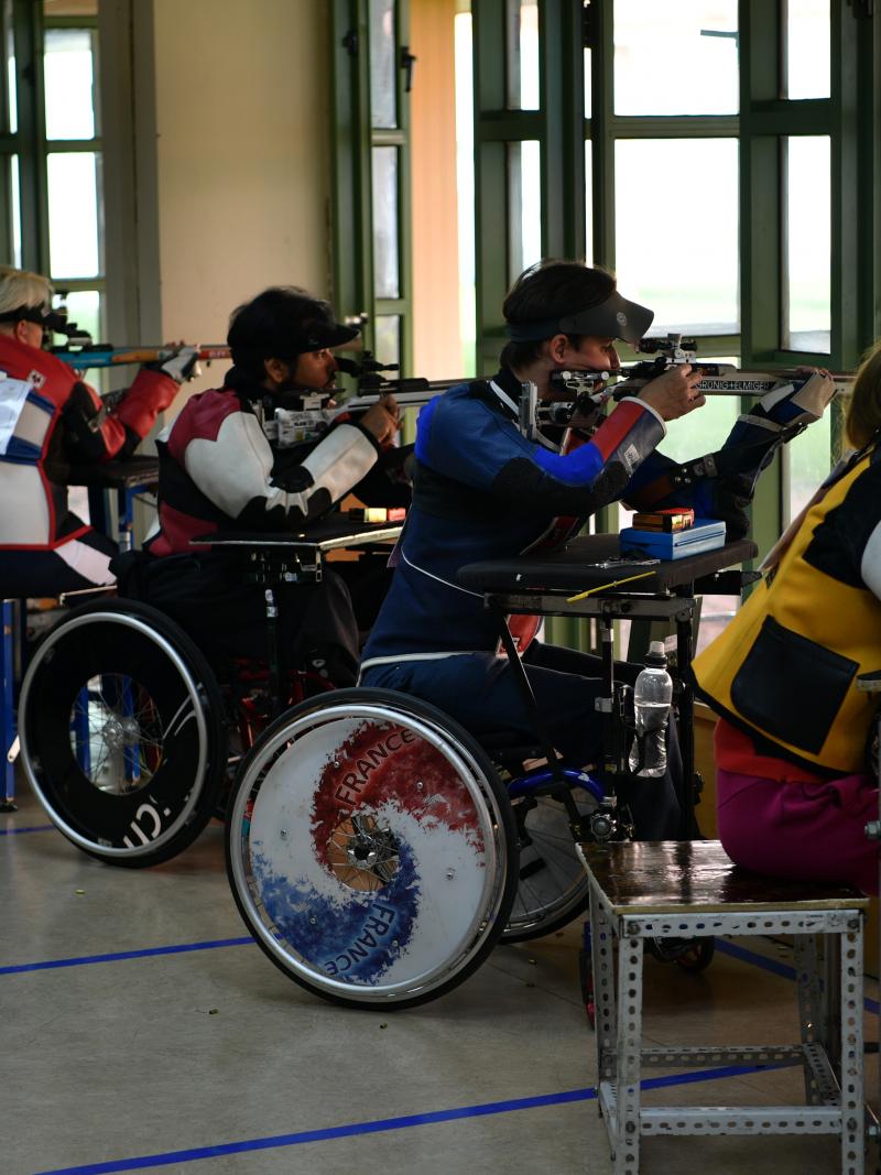 Para shooters sitting in wheelchairs firing rifles on the range