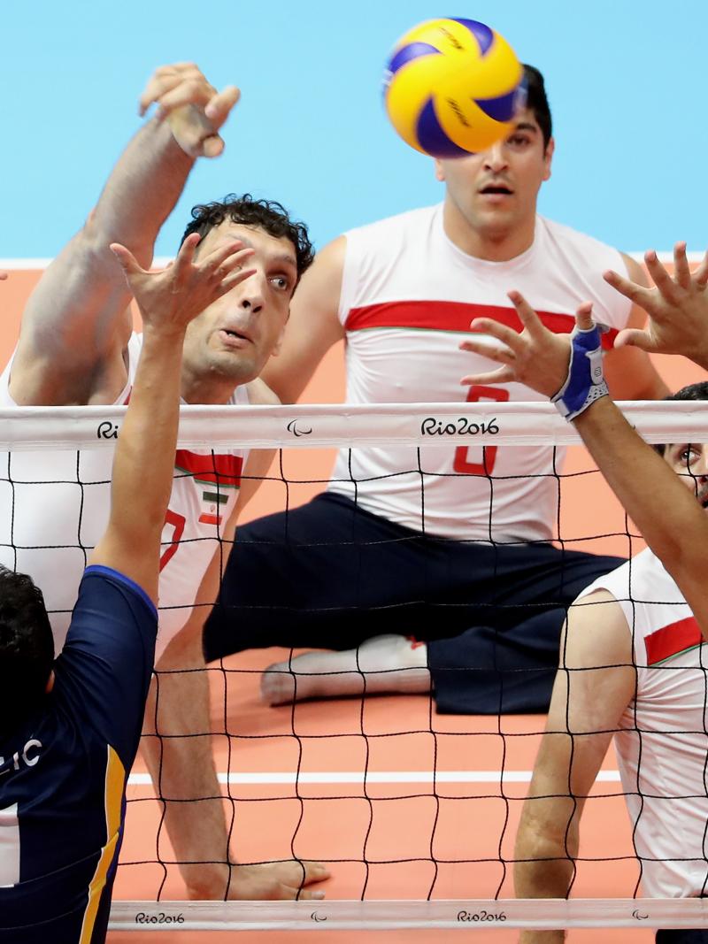 a group of male sitting volleyball players on court during a match