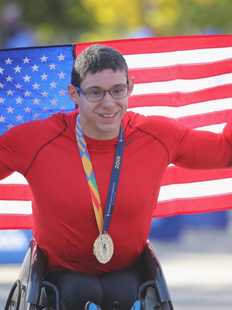 male wheelchair racer Daniel Romanchuk holding up a USA flag