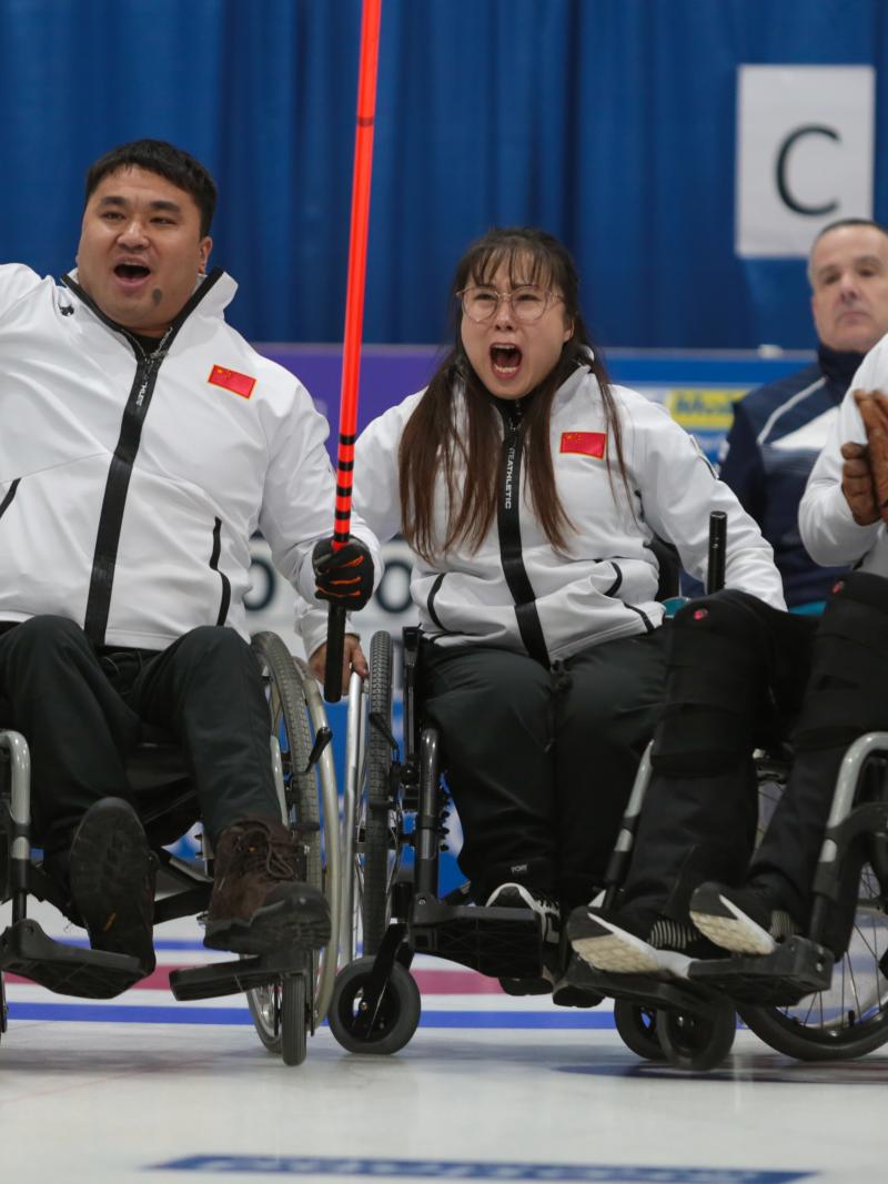 Three Chinese wheelchair curlers celebrate expressively on the ice