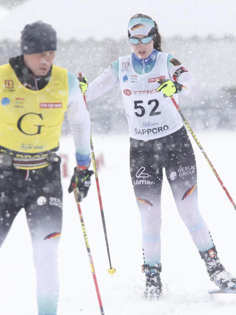 female Para Nordic skier Clara Klug skis towards the finish line behind her guide