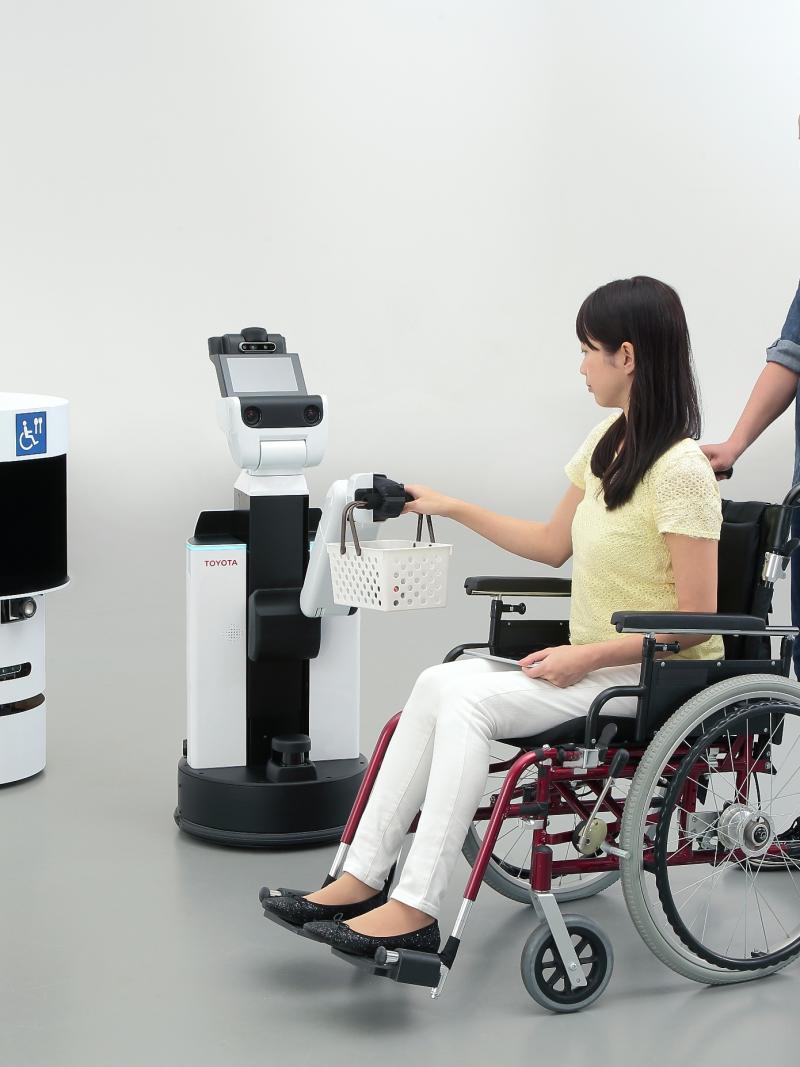 a person in a wheelchair having their basket held by a robot