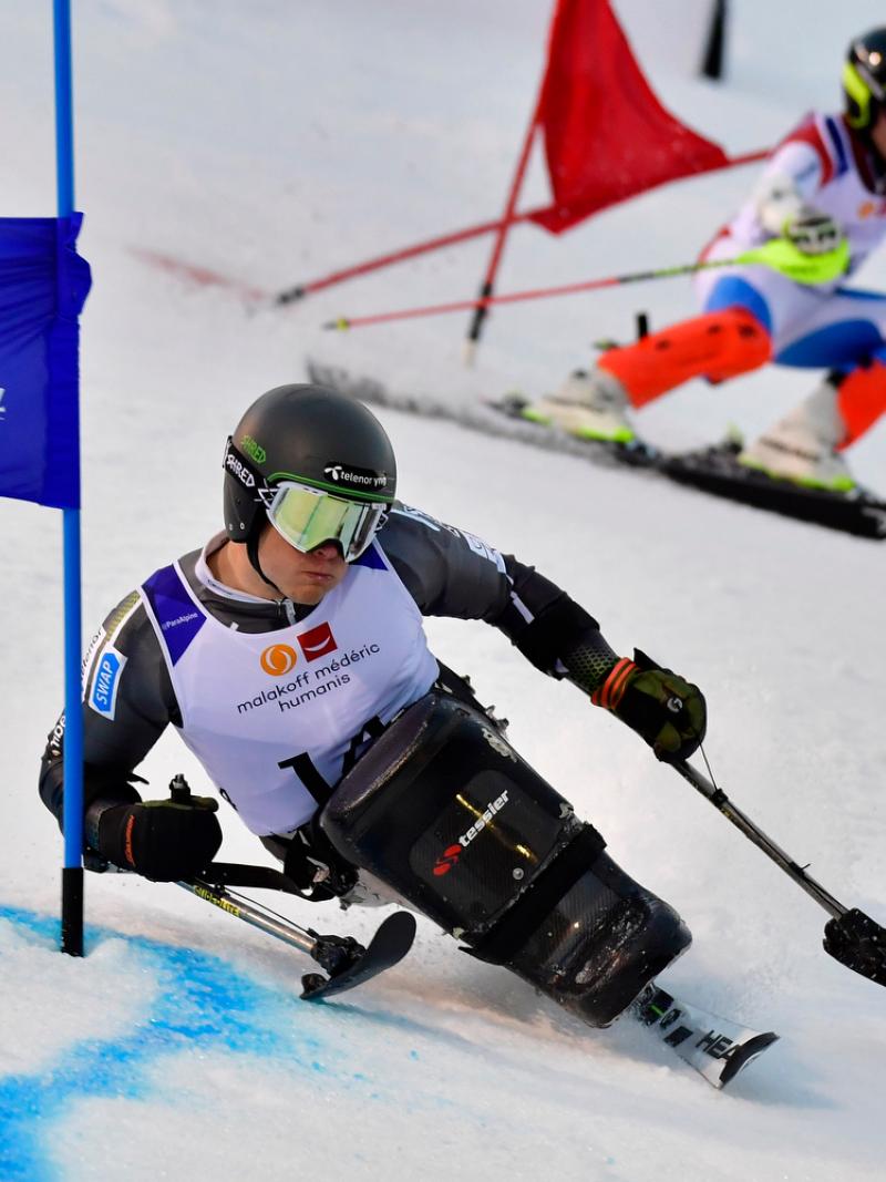 male sit skier Jesper Pedersen races head to head with a standing skier