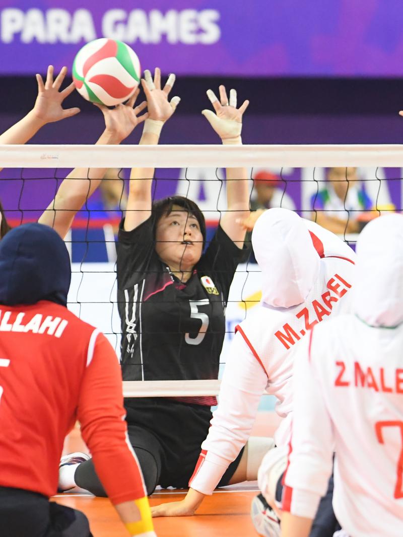 two female sitting volleyball teams contesting the ball on court