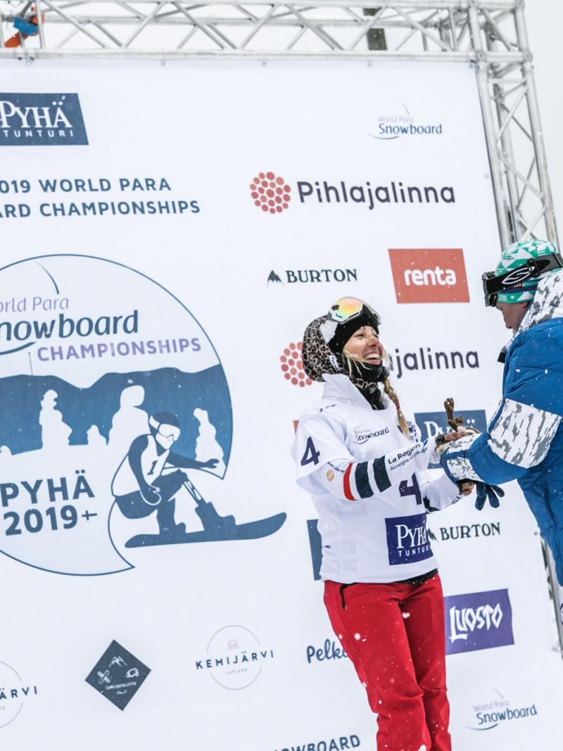 female Para snowboader Cecile Hernandez accepts her gold medal on the podium