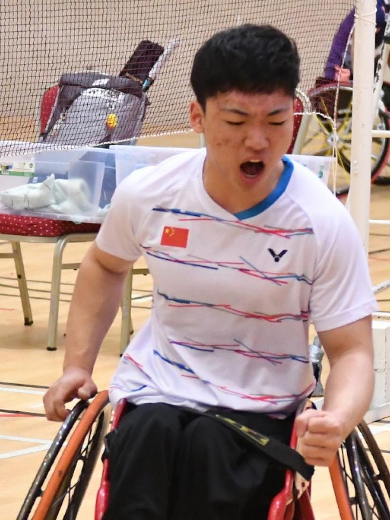 a male Para badminton player in a wheelchair pumps his fist after winning a point