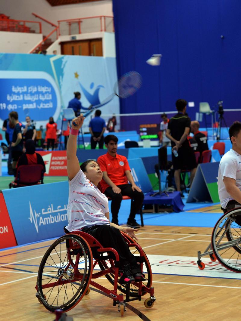 male and female Chinese Para badminton players in wheelchairs playing on the court