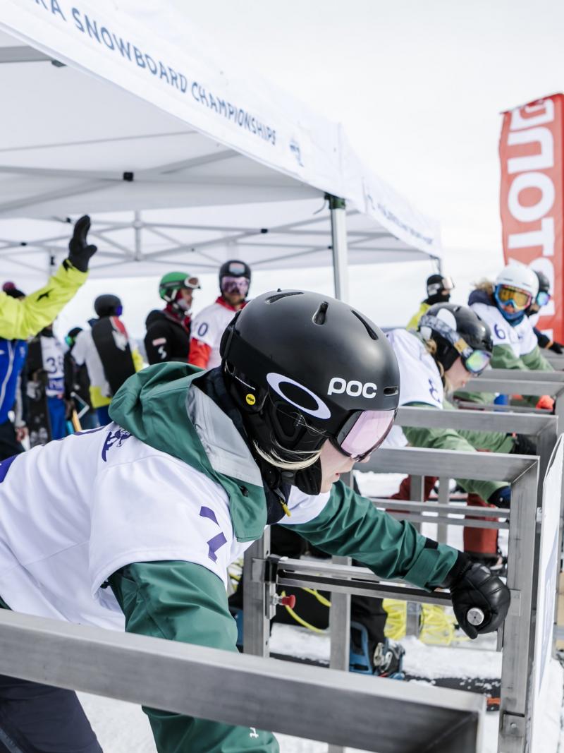 Female snowboarders line up at the start gate ready to go