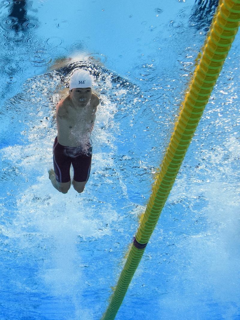 An armless man swimming next to a short stature man
