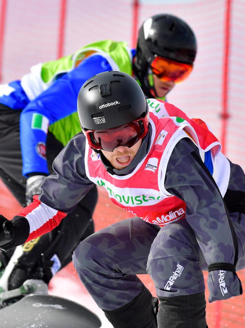 male Para snowboarder Patrick Mayrhofer rides in front of another snowboarder