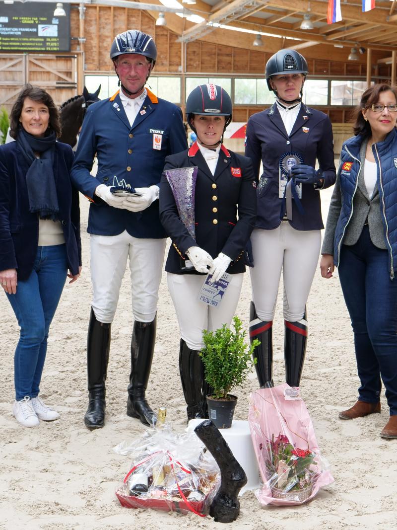 A group of people standing on a dressage arena