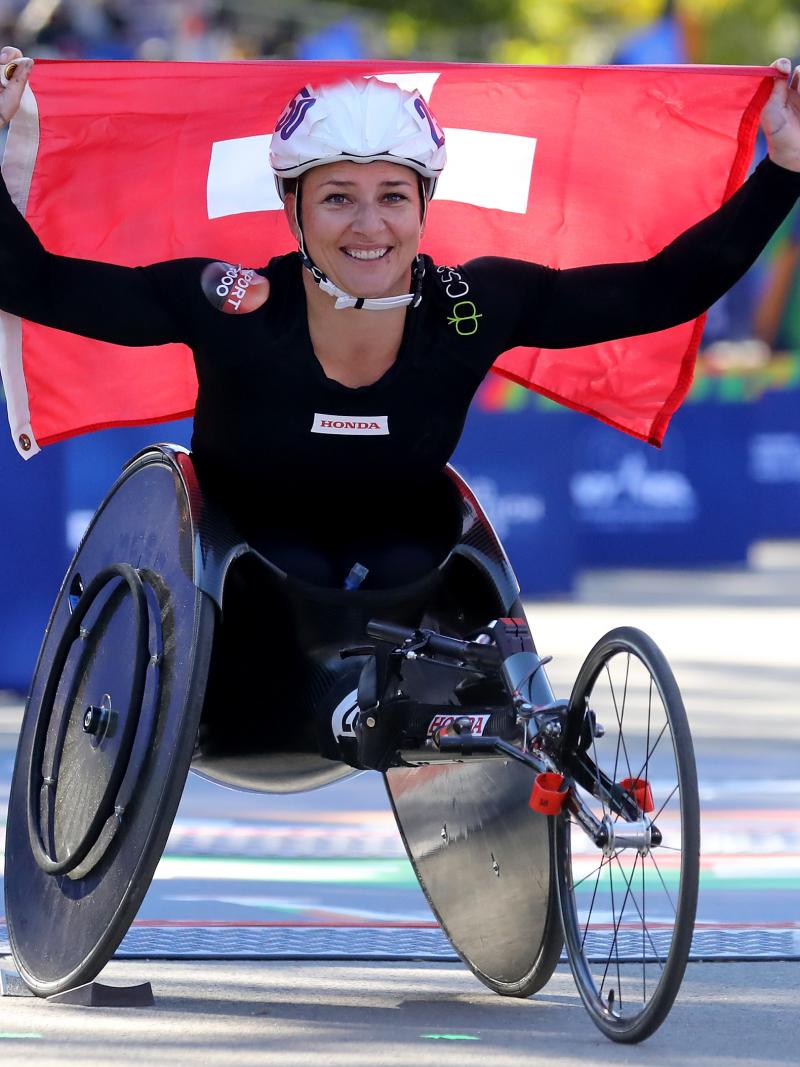 female wheelchair racer Manuela Schaer holding up a Swiss flag