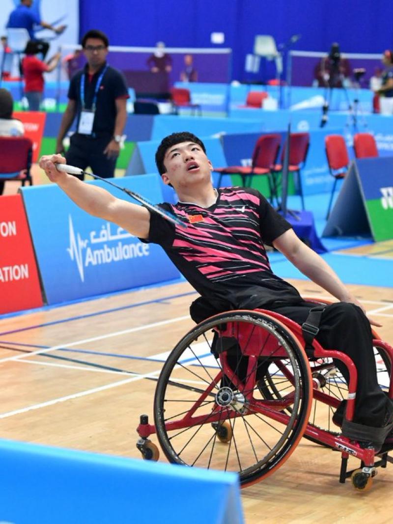 male Para badminton player Qu Zimao goes for a backhand shot on court