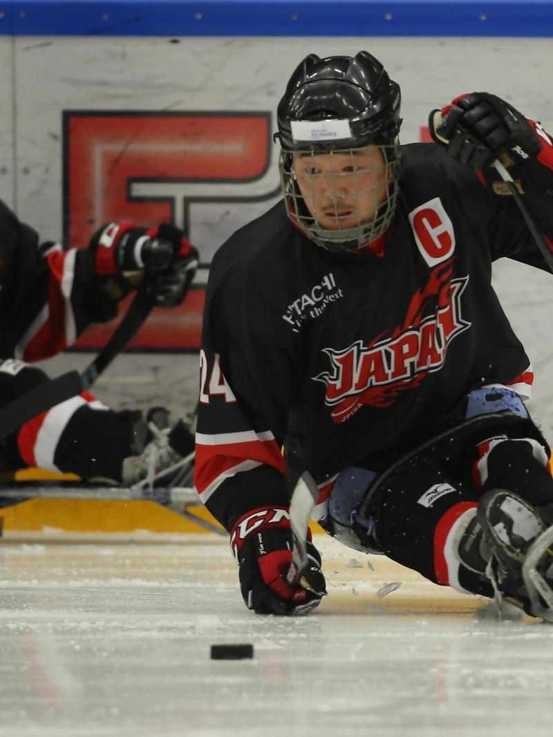 Japanese male Para ice hockey player skates with the puck