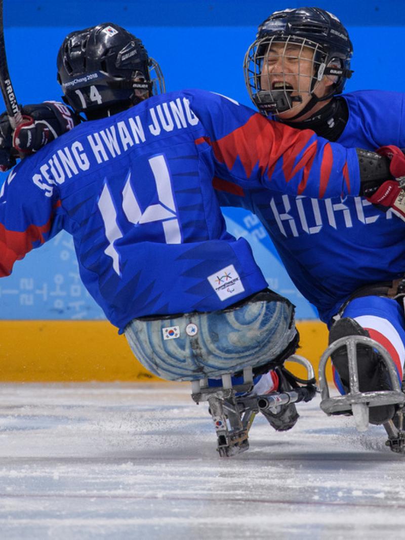 Two Para ice hockey players hug on the ice rink