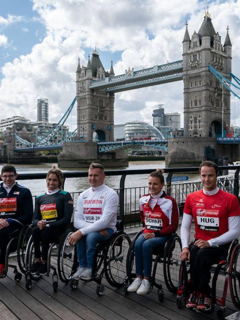 Five wheelchair athletes sitting in a row at the edge of the River Thames with London's Tower Bridge in the background