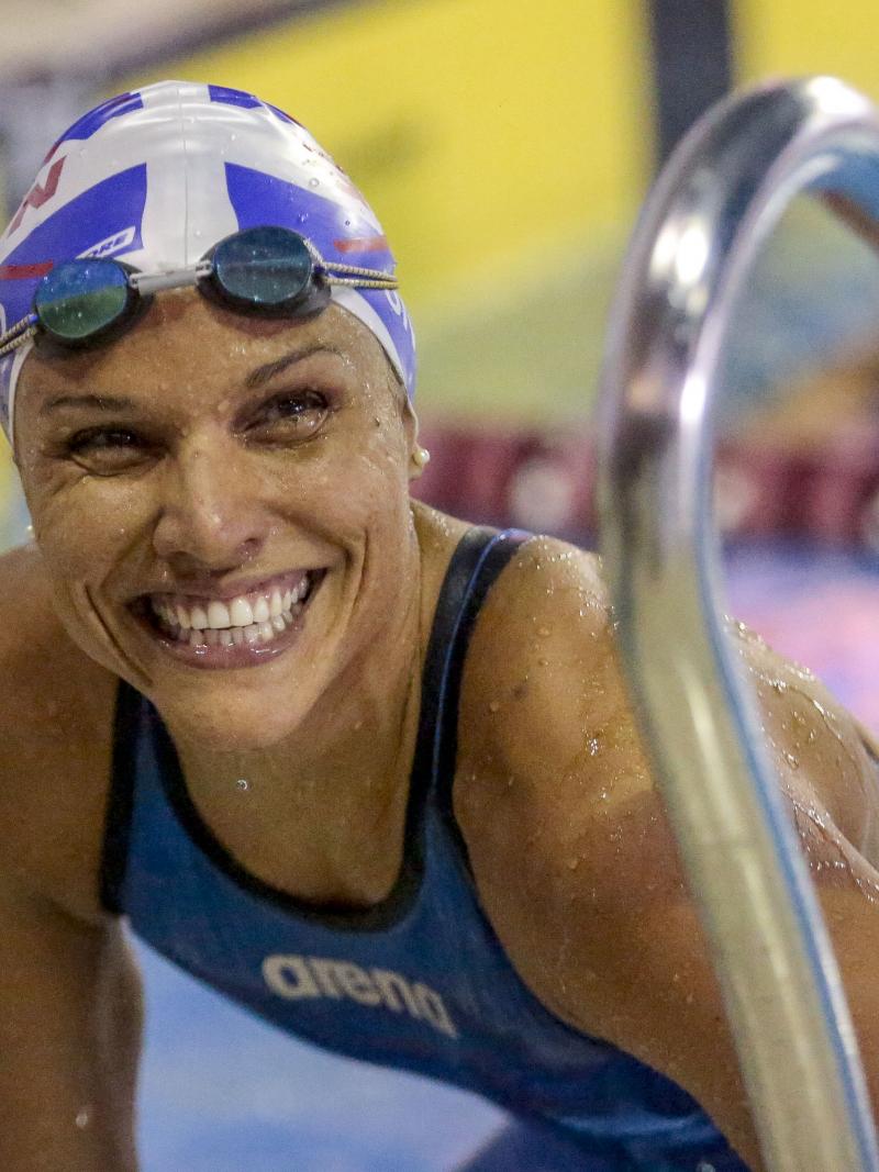 Female Para swimmer Maria Carolina Gomes smiles in the pool while leaning on the steps