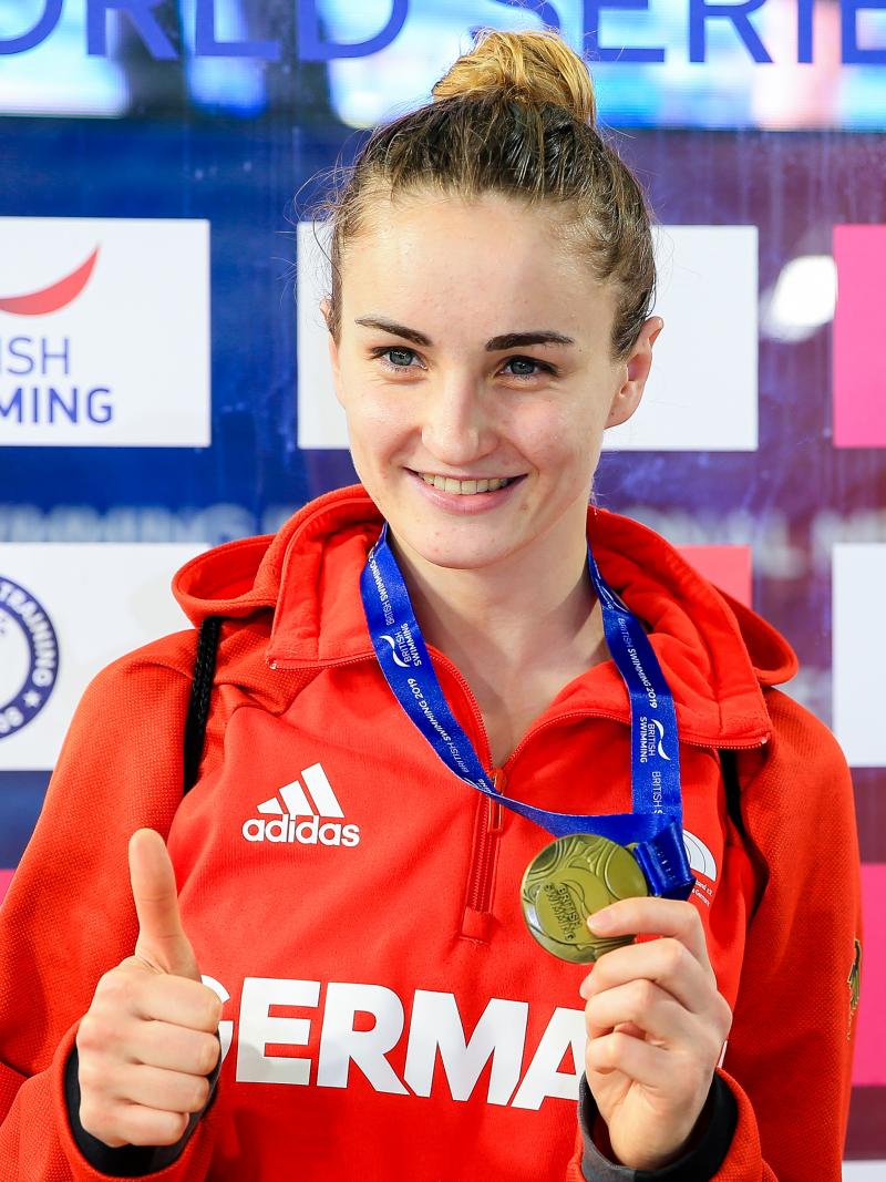 female Para swimmer Elena Krawzow gives a thumbs up and holds up her gold medal 