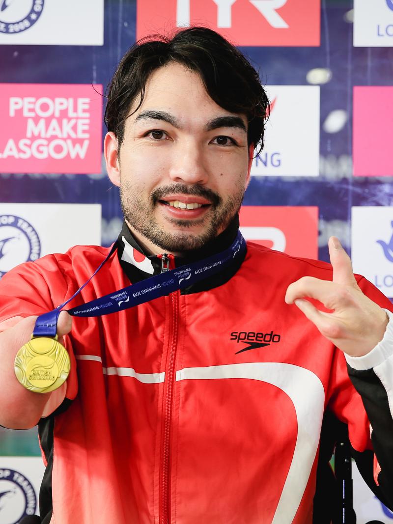 male Para swimmer Takayuki Suzuki holds up his gold medal