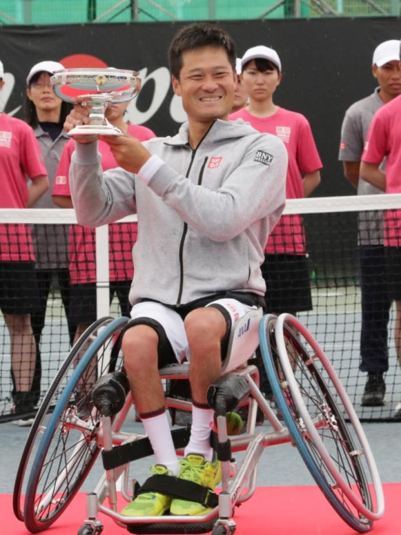male wheelchair tennis player Shingo Kunieda smiling and holding up a silver trophy