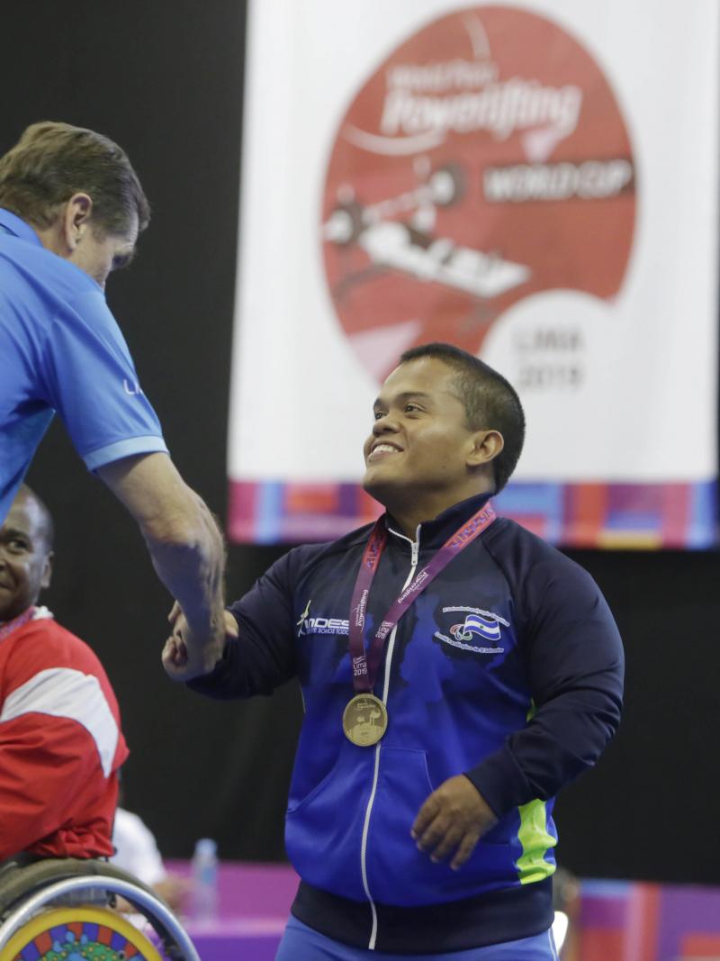 male Para powerlifter Herbert Aceituno shaking hands with an official