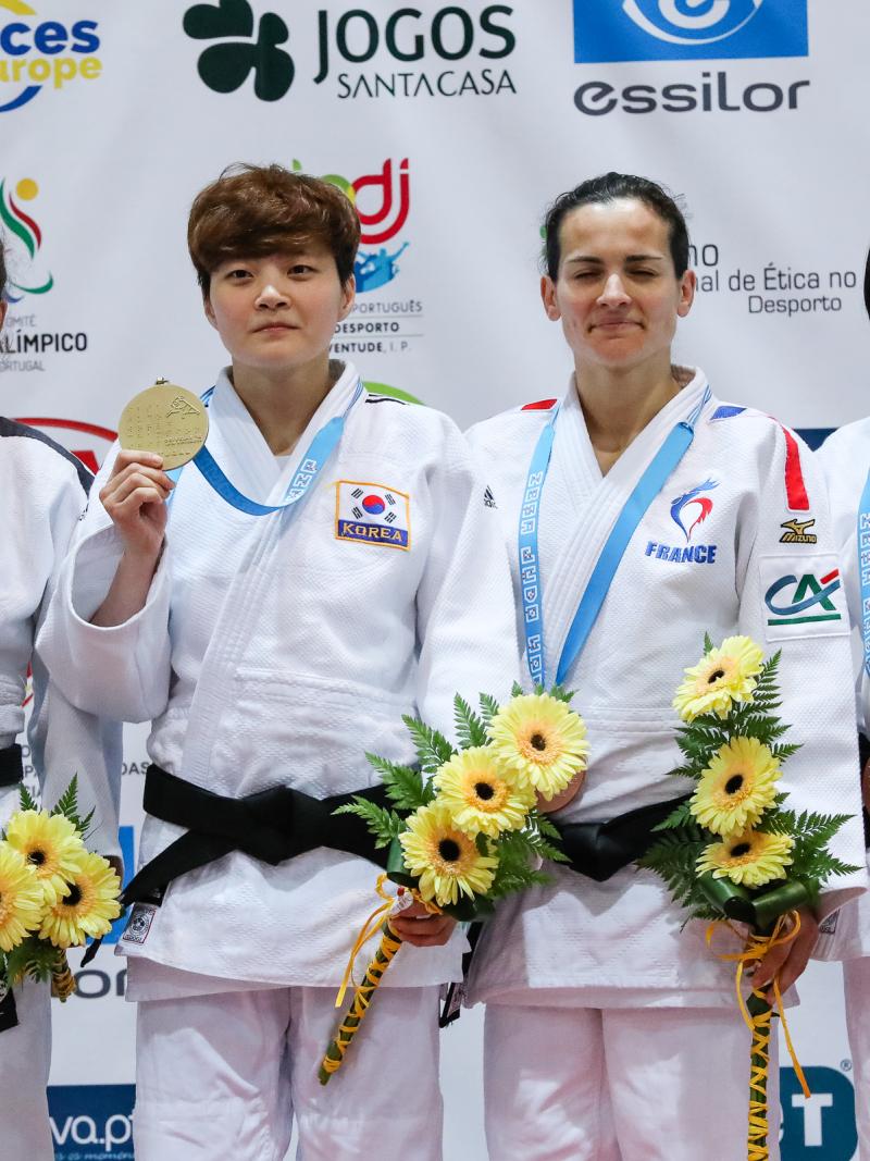 female judoka Sandrine Martinet on the podium holding her medal