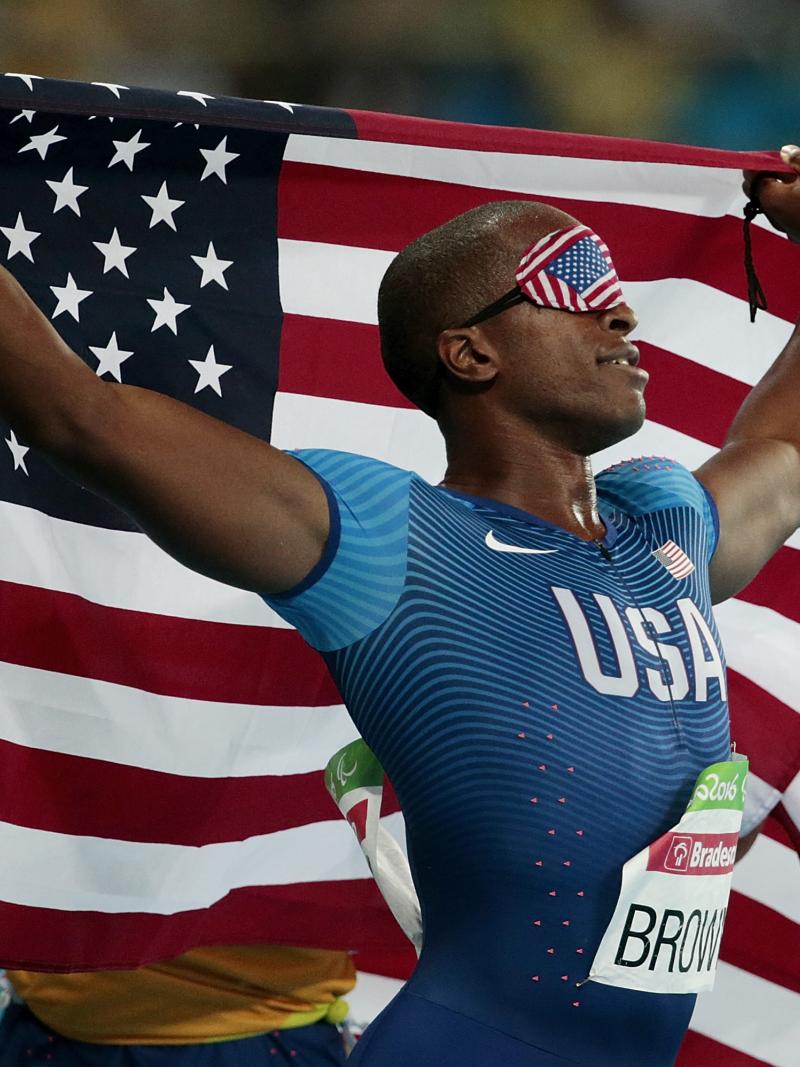 male vision impaired sprinter David Brown holding up the USA flag 