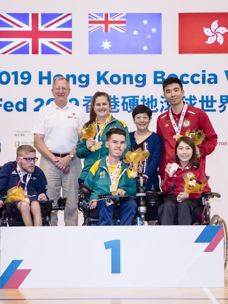 Podium photo with three boccia players and their assistants posing for a photo