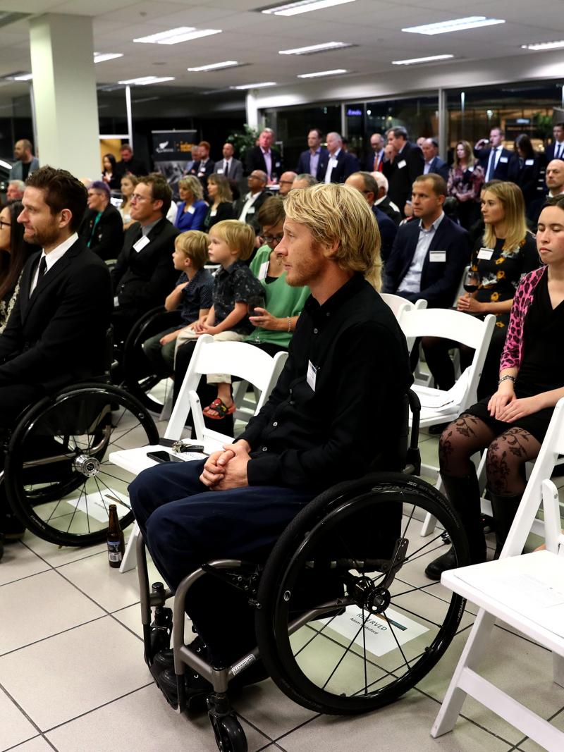 People gathered inside a room looking to the front and listening to a speaker