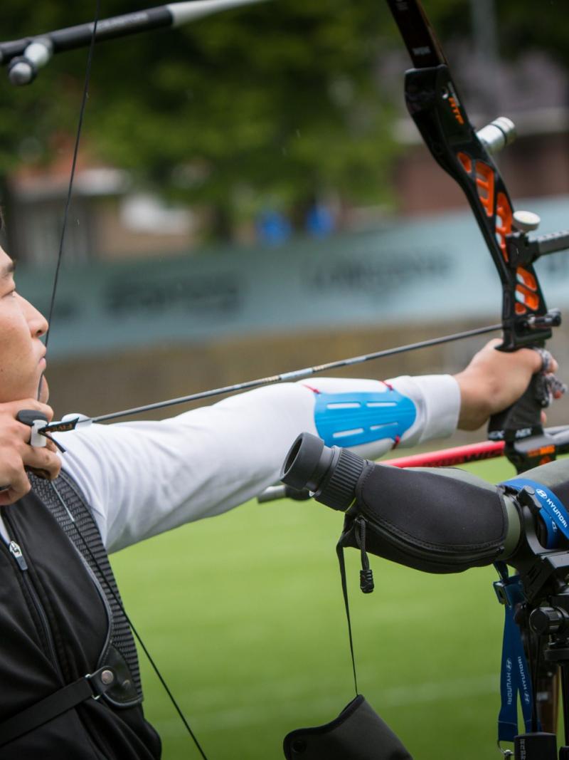 Korean male archer pulls back on his bow string aiming for a target