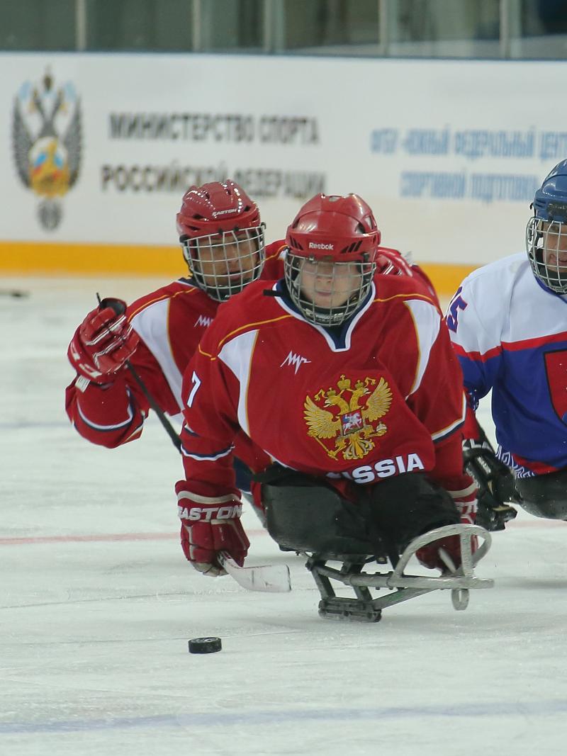 Two Russia Para ice hockey players and one Slovakian race for the puck
