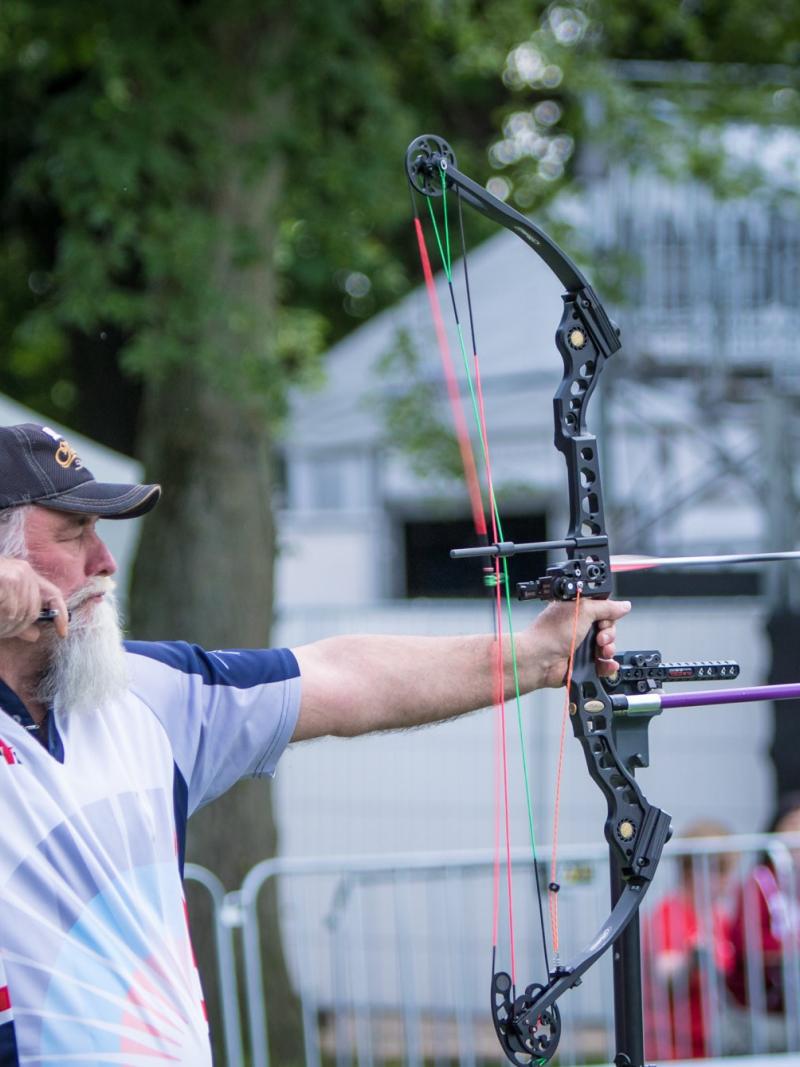 Man with long white beard shoots his bow and arrow