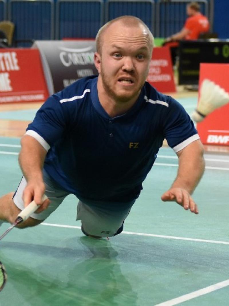 Short statured English badminton player dives for the birdie
