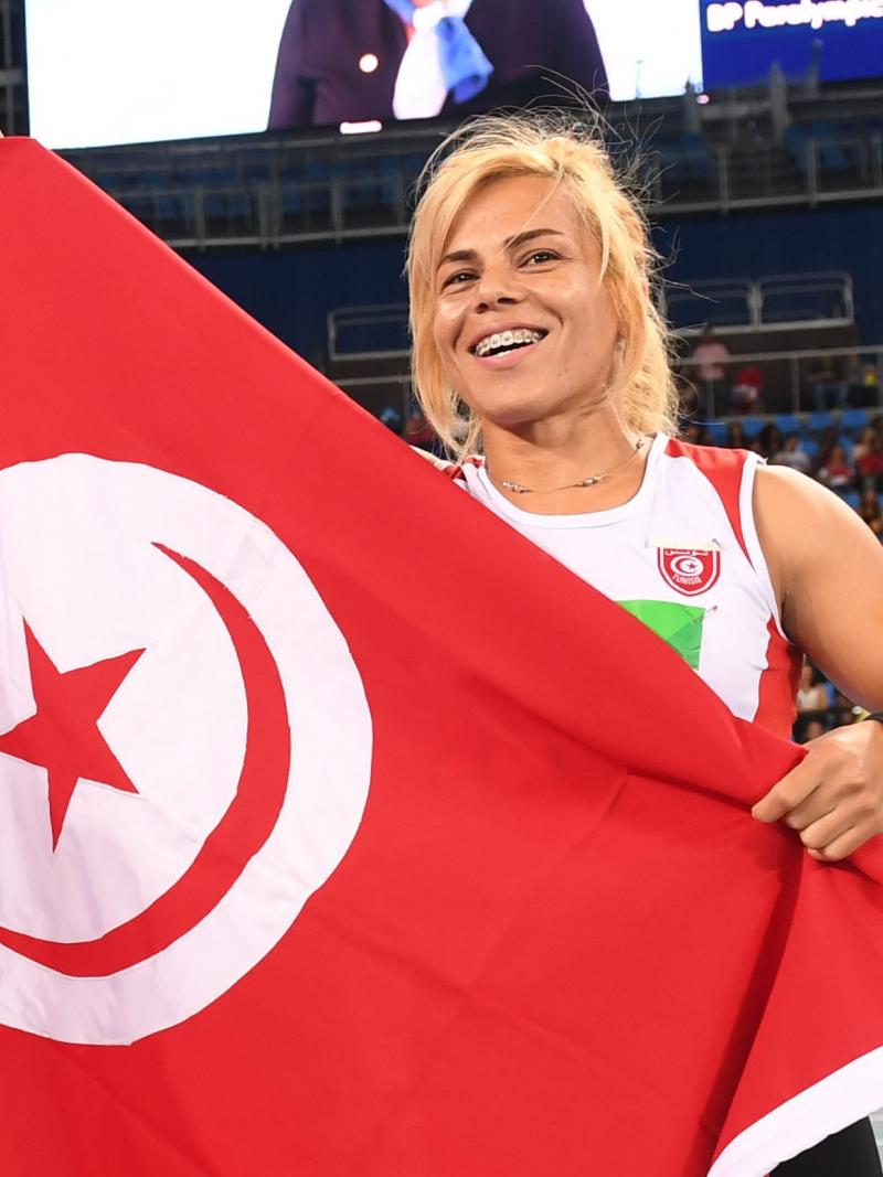 female Para athlete Raoua Tlili holds up the Turkish flag and smiles