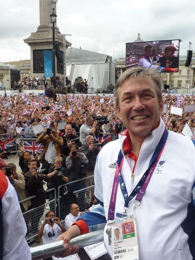 British man in wheelchair smiling in front of a big crowd of people