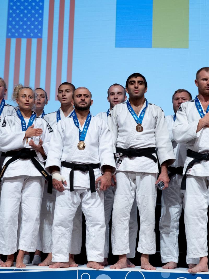 A group of vision impaired female and male judokas on the podium