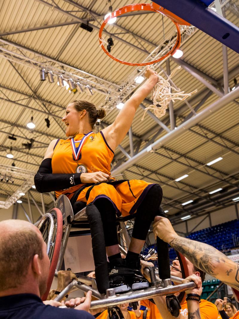 Dutch female being lifted up on her wheelchair to the basketball hoop