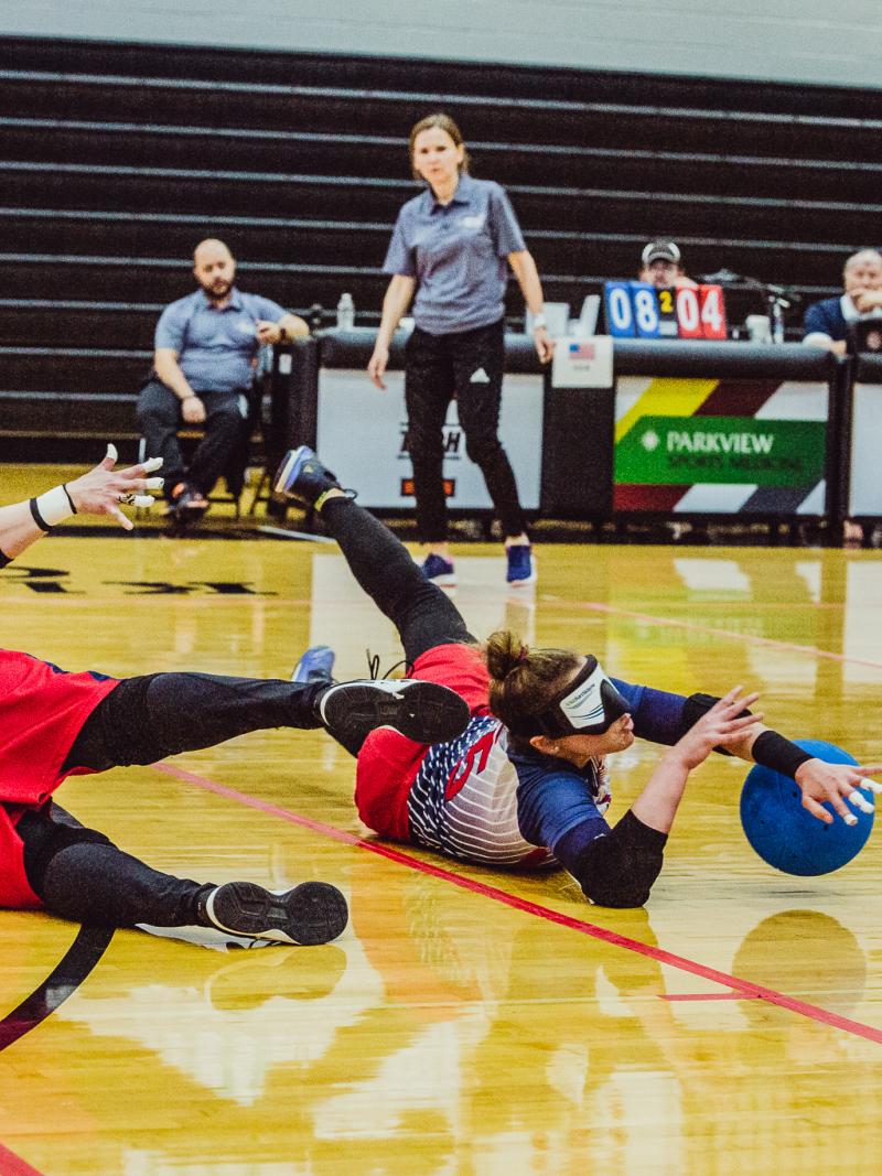A female goalballer slides to block the ball from entering the goal