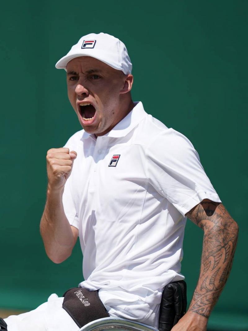 British male wheelchair tennis player clutches fist to celebrate a point