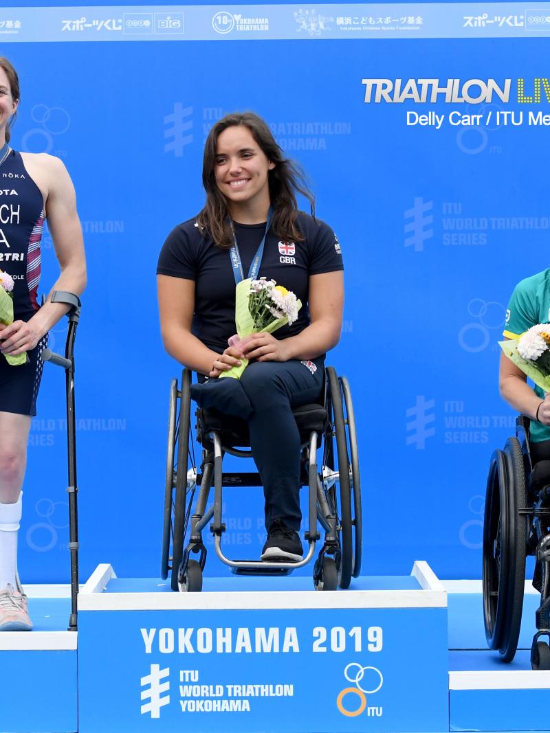 Three female triathletes on a podium smiling