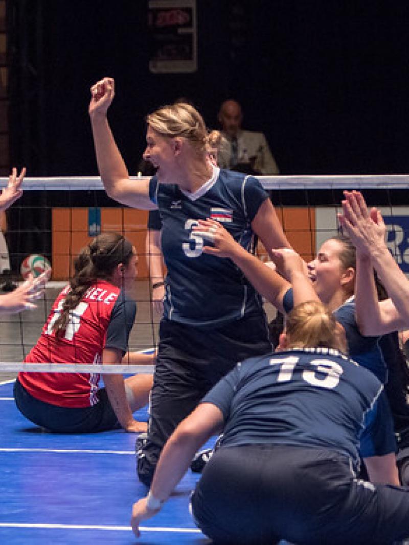Russian sitting volleyball players celebrate together on the court after a point