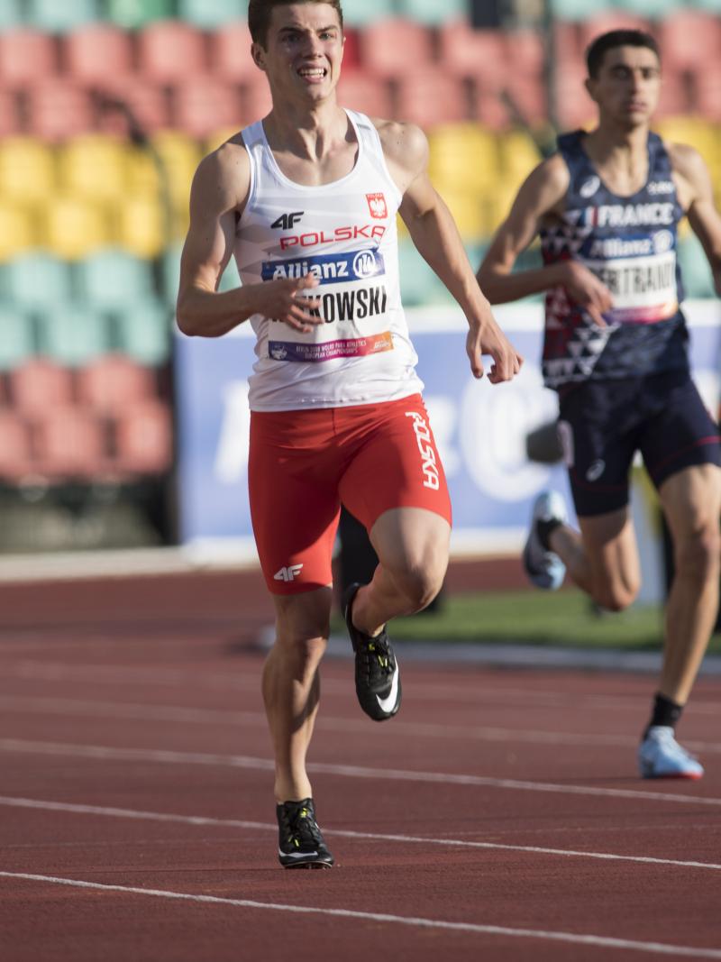 A male sprinter runner ahead of two other competitors