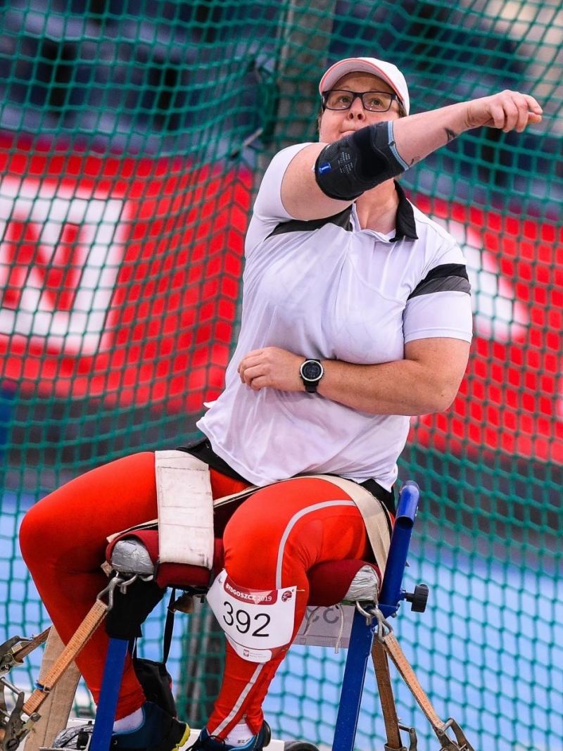 Polosh woman sits in chair and throws a discus
