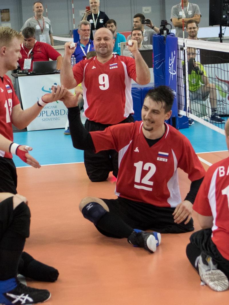 Russian men's sitting volleyball players celebrate on the court after scoring a point