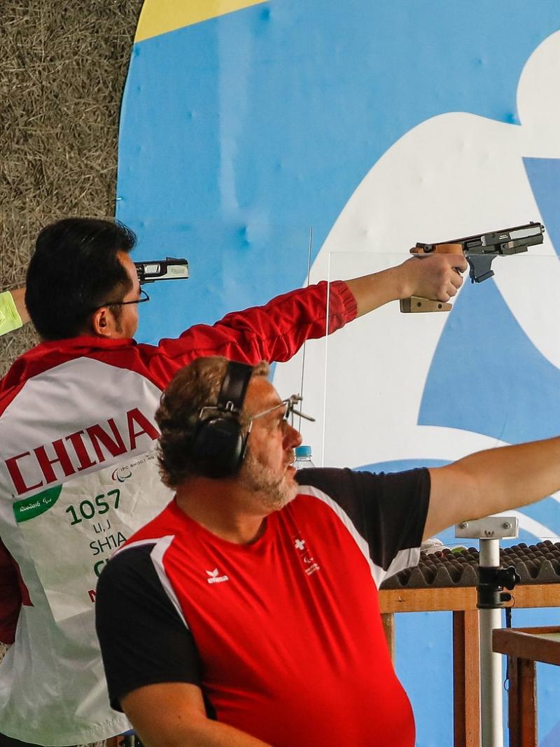 A one-legged woman and two men competing at a shooting range