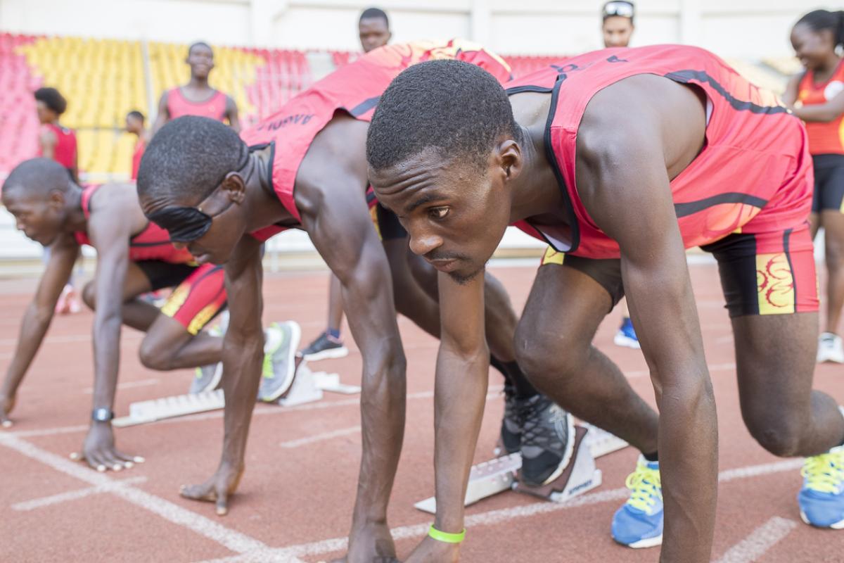 Athletes and guides prepare in starting blocks during Agitos Foundation training camp in Luanda